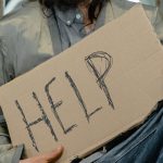 person in gray shirt holding brown cardboard
